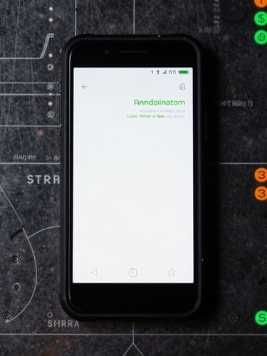 A macro flat lay of a rugged Android phone on a dark metal blueprint table, screen showing a clean terminal-style interface with green text, high contrast