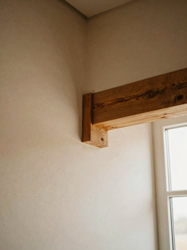 Tight tactile detail of a raw timber joint against textured warm plaster, soft side daylight