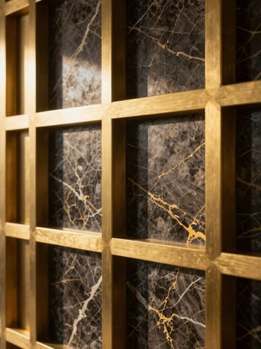 Close-up of premium building materials, bookmatched dark marble with gold veins, brushed brass architectural details, dramatic side lighting, luxury interior detail