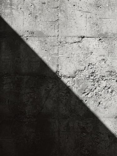 Extreme close-up of a sharp shadow cast across a textured concrete wall, minimalist architectural photography, high-contrast hard sunlight, monochrome desaturated tones, 35mm