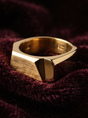 Macro studio shot of a thick 9-carat gold ring with clean geometric lines, resting on dark textured burgundy velvet, soft directional gold lighting, dramatic shadows.