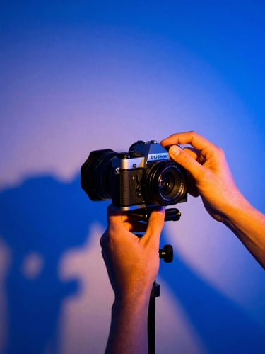 High-contrast studio photography setup, hands adjusting a vintage camera rig under dramatic blue neon lights, sharp shadows