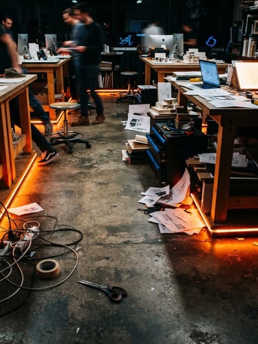 Dynamic low angle shot of a physical design studio floor, vibrant orange neon edge-lights casting sharp shadows on concrete, 35mm film grain
