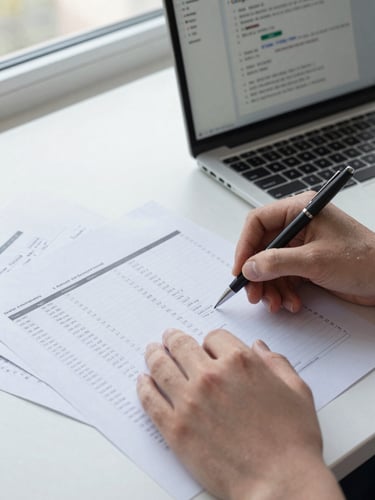 Close-up of hands annotating a printed performance report on a desk, a laptop screen showing Google Ads campaign metrics visible in the background, north-facing daylight from a window casting clean even light, no glare, papers and a pen in sharp focus