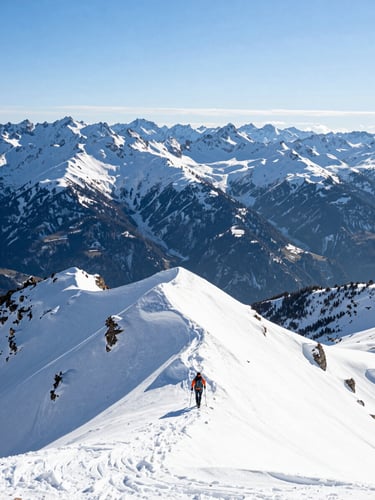 Vast sunlit mountain range with a tiny human figure climbing a pristine snow ridge under crisp morning daylight, wide environmental scale