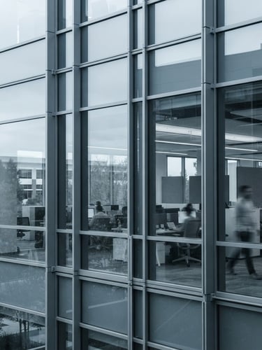 Modern architectural detail of a Silicon Valley workspace glass facade, bright indirect daylight, cool desaturated tones with sharp contrast, 35mm lens, editorial style