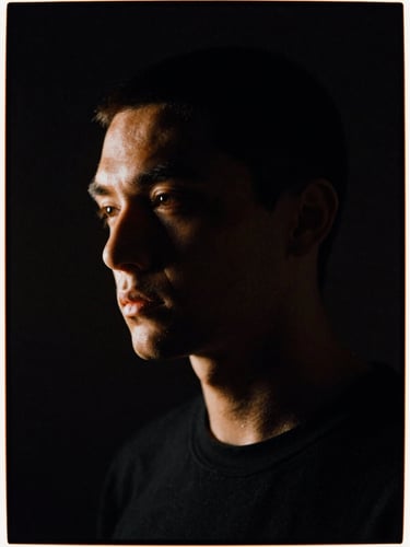 High-contrast portrait of the artist in a dark studio, single-source side lighting, warm orange rim lights, 35mm film grain