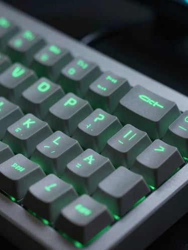 Macro close-up de um teclado de computador moderno com teclas iluminadas em verde, refletindo um código limpo em uma tela, em um ambiente de trabalho escuro com iluminação de estúdio fria.