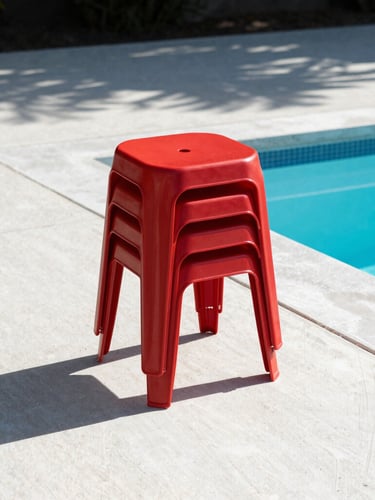 A stack of three bold red monobloc resin stools casting sharp geometric shadows on clean concrete poolside tiles, harsh midday sun, architectural framing