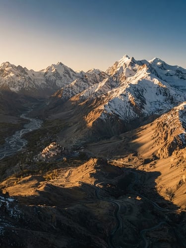 Dramatic wide-angle drone shot of snow-capped Himalayan peaks in Ladakh, sharp ridges casting long shadows under natural high-altitude golden hour sunlight, 35mm film style.