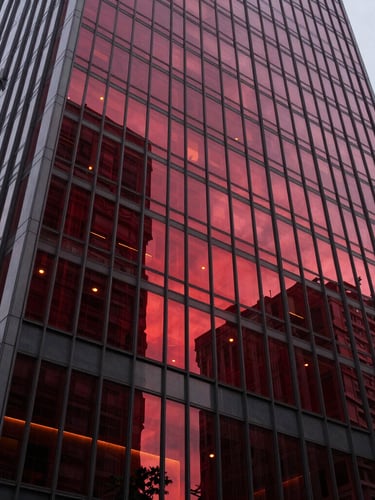 Wide-angle architectural shot of a modern glass skyscraper facade in São Paulo, sharp focus, deep crimson light reflections, high-end editorial style