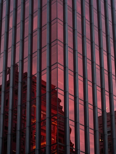 Sleek modern corporate skyscraper facade, dramatic architectural lighting, deep crimson reflections on glass, sharp focus, high-end editorial style