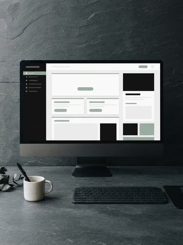 Straight-on flat lay of a minimalist workspace with a slate desk, a high-contrast web layout displayed on a clean monitor, soft natural side-light, muted sage accent on screen
