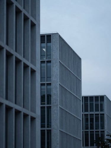 Minimalist architectural lines of a modern financial district building at dusk, cool overcast daylight, desaturated blues and slate tones, shallow depth of field, 35mm