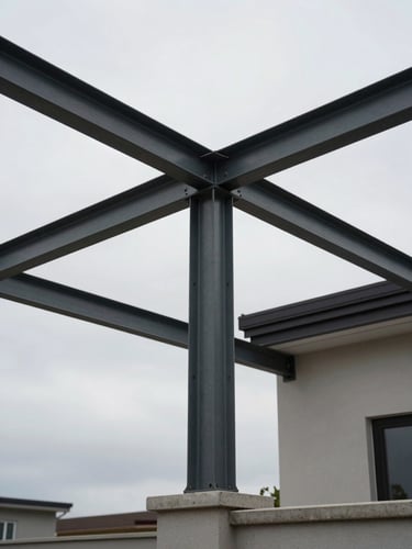 Wide low-angle shot looking up at a steel canopy frame installed over a residential terrace, structural beams and cross-members visible against an overcast midday sky, concrete anchoring posts in foreground, no people