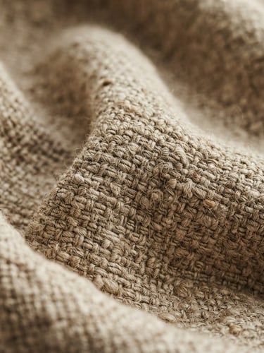 Macro texture shot of heavy-weight natural linen weave, soft diffused window light, gentle shadows in the deep folds, warm earth tones