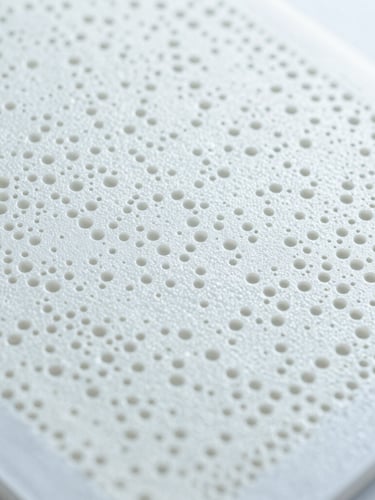Extreme close-up of a biocompatible polymer membrane structure, porous medical grade material, sterile clinical laboratory lighting, cool white and slate tones