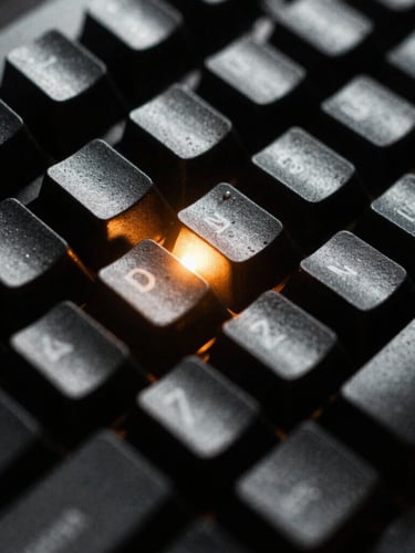 Extreme close-up macro shot of a rugged mechanical keyboard with custom keycaps, harsh single-source cold light from the side, deep shadows, amber terminal glow reflecting on the matte black keys, 35mm film grain.
