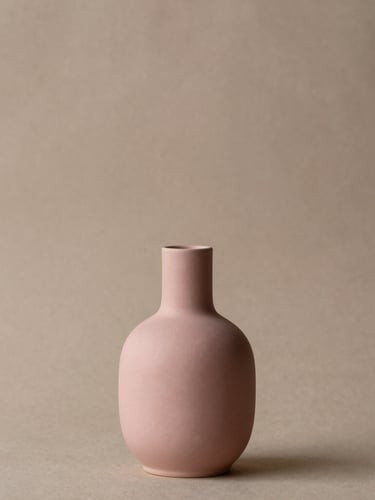 Elegant editorial photography of a single, architectural dusty rose in a minimalist ceramic vase, soft side-daylight, warm taupe plaster backdrop, 35mm