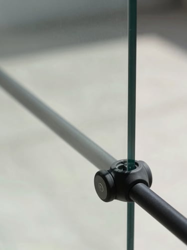 Macro detail of a clean black silicone seal on a thick frameless glass pane, modern architectural context, bright natural daylight, sharp reflections, minimal geometric composition