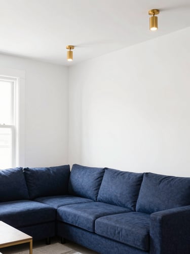 Bright interior photography of a modern Nashville living room, natural daylight, navy blue accents, clean white walls, warm gold light fixtures, sharp focus