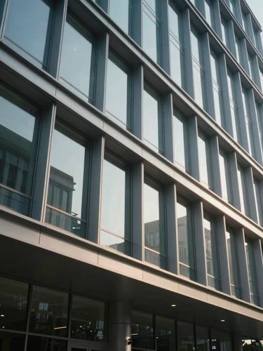 Wide environmental architectural shot of a modern corporate building facade with clean steel lines and glass panels, cool-toned natural daylight, soft realistic shadows.