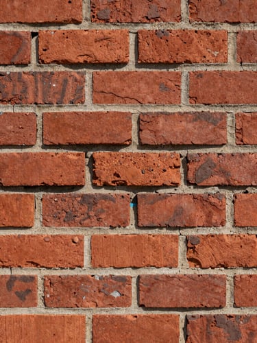 Straight-on documentary shot of a freshly struck tuckpointed brick wall, clean deep mortar joints, rough red brick texture under harsh daylight
