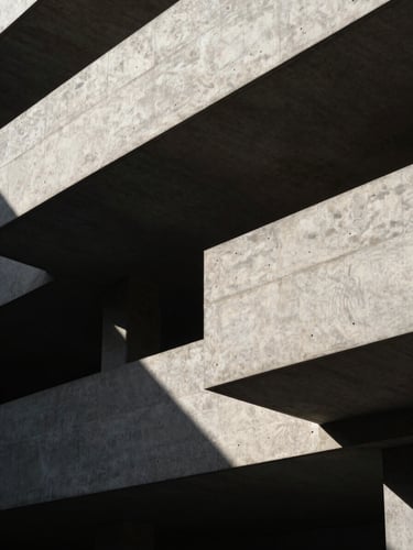 Abstract architectural geometry of a modern concrete building with strong shadows and sharp linear highlights, low-key dramatic side-lighting.