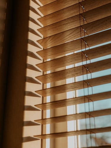 Natural wood horizontal window blinds with sunlight filtering through for home decor.