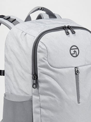 Bright high-key product photography of a technical travel backpack showing reinforced seams and heavy-duty zippers, clean neutral studio background, 50mm