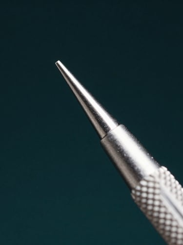 Extreme macro close-up of a surgical dental forceps tip, focusing on the textured knurling of the handle and the sterile silver-gray metallic bevel, sharp studio lighting, deep obsidian background.