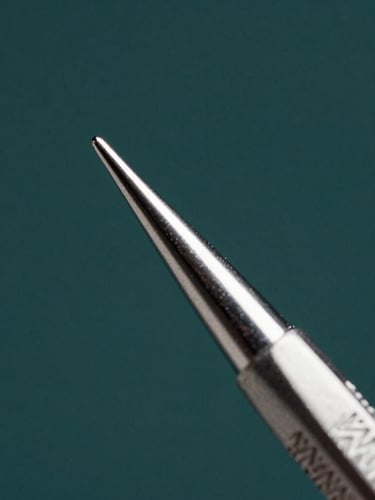 Macro close-up of a surgical elevator tip, high-contrast studio key light with sharp metallic reflections, cool silver-gray undertones, extreme depth of field