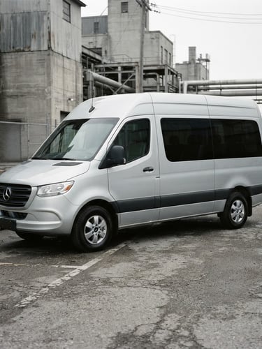 Crisp automotive photography of a clean modern passenger van parked in a desaturated industrial environment, overcast daylight, 35mm lens