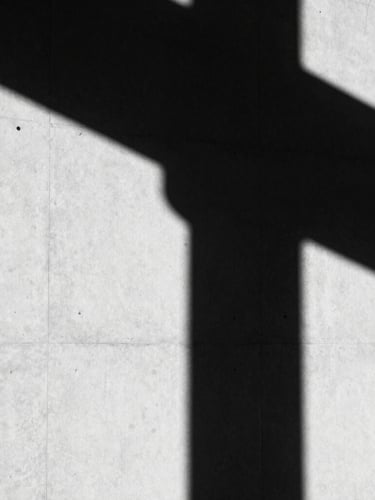 High-contrast black and white photography, dramatic architectural shadows on a clean concrete wall, minimalist editorial composition, sharp focus