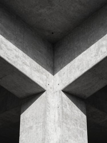 Symmetrical architectural detail of a concrete cantilever structure, harsh natural light, sharp geometric shadows, minimalist composition
