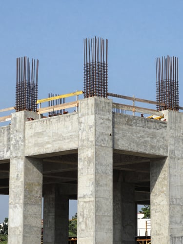 Wide environmental shot of a massive concrete bridge foundation under construction in Colombia, steel reinforcement bars visible, bright natural daylight, crisp focus, 35mm