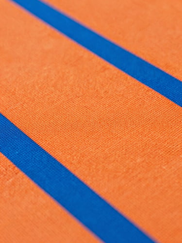 Crisp macro shot of textured technical athletic fabric, vibrant orange and blue fibers under high-key studio lighting, sharp focus