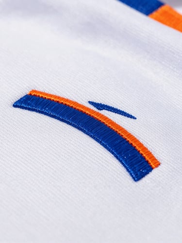 Bright natural light, macro shot of textured technical athletic fabric with clean custom embroidery, vibrant blue and orange threads, shallow depth of field