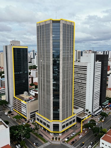 High-altitude drone photography of a prime vacant commercial corner lot in a major Brazilian city, sharp yellow vector-style boundary line overlay, crisp overcast daylight