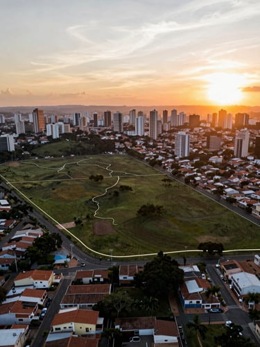 High-altitude drone photography of a raw residential land parcel in São Paulo, sharp sunset light, subtle vector boundary overlay highlighting the terrain