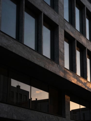 Abstract architectural lines of a modern concrete and glass building at dusk, subtle gold ambient light cutting through deep shadows, dark editorial photography.