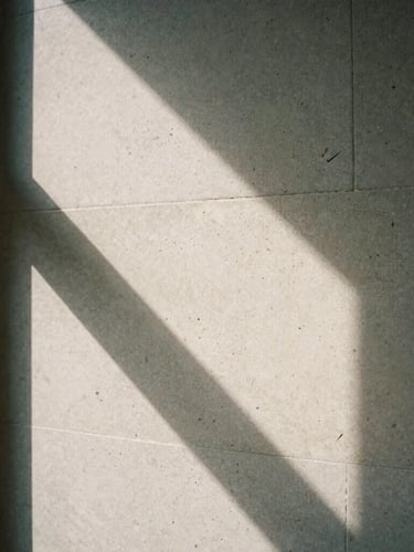 Macro close-up of natural light casting deep graphic shadows across a textured travertine stone wall in a quiet Manhattan office, sober editorial photography, 35mm film