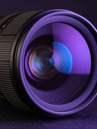 Cinematic close-up of a high-end anamorphic camera lens, deep purple and electric blue neon reflections on the glass, dark studio background, shallow depth of field.