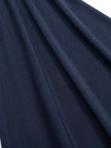 Close-up of a perfectly pressed black abaya fabric showing elegant fine weave and clean folds under bright natural light