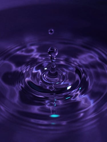 Macro close-up of water ripples spreading from a single point, deep violet water with sharp neon teal light highlights, high-contrast chiaroscuro, 35mm lens