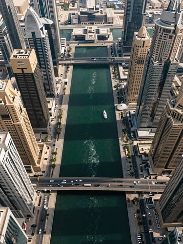 Elevated straight-down aerial photograph of Dubai's central districts — the Marina canal, Downtown grid, DIFC cluster, and Palm fronds visible simultaneously under sharp midday architectural light, no people, pure urban geometry at scale