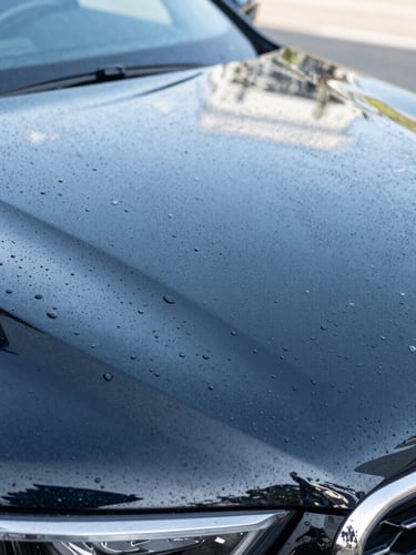 Macro shot of water beading perfectly on a freshly waxed black car hood, crisp daylight highlighting the sharp reflections, professional detailing finish.