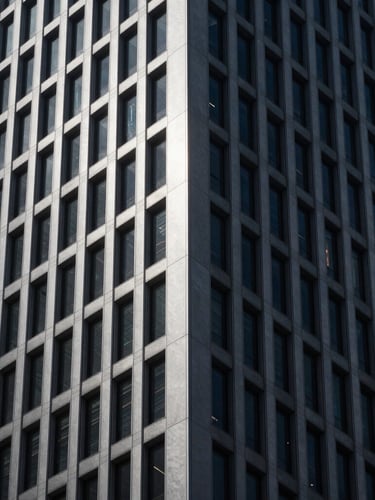Sleek architectural photography of a monolithic corporate tower corner, dramatic low-key lighting, deep obsidian and cool silver tones, sharp focus, 35mm.