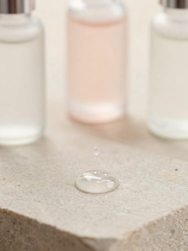 Macro shot of a single pristine serum droplet suspended on a clean stone surface, soft morning light, 85mm