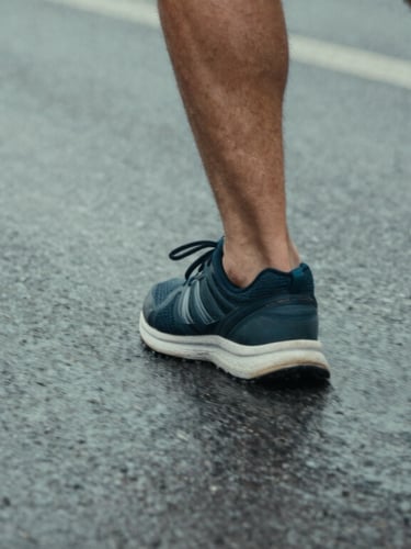 Close-up of running shoes on wet asphalt with dynamic motion blur, overcast northern daylight, cool desaturated tones, 35mm film style